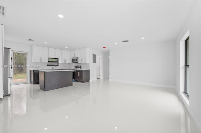 kitchen featuring white cabinetry, a kitchen island, stainless steel appliances, and tasteful backsplash