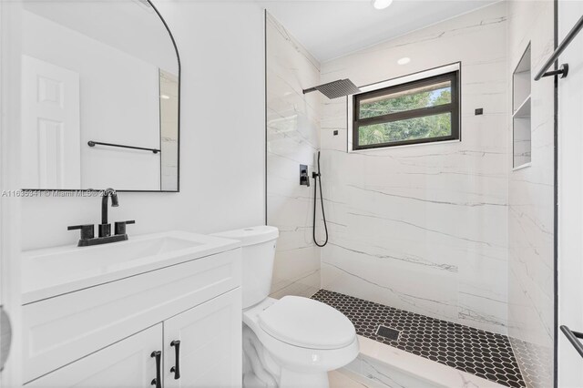 bathroom with tiled shower, toilet, and vanity