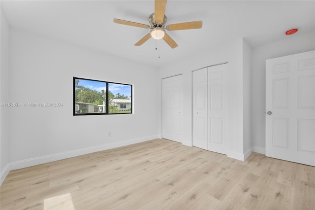 unfurnished bedroom with two closets, ceiling fan, and light hardwood / wood-style floors