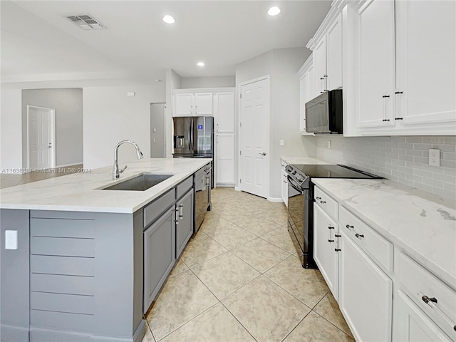 kitchen featuring light tile patterned floors, range with electric cooktop, sink, and white cabinetry