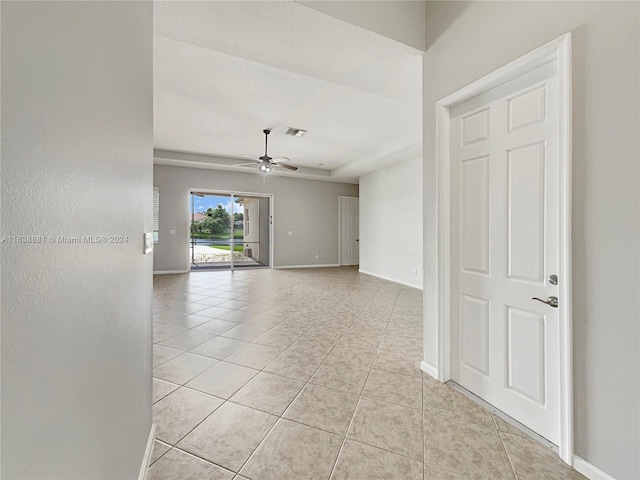 unfurnished room featuring ceiling fan, light tile patterned flooring, and a raised ceiling