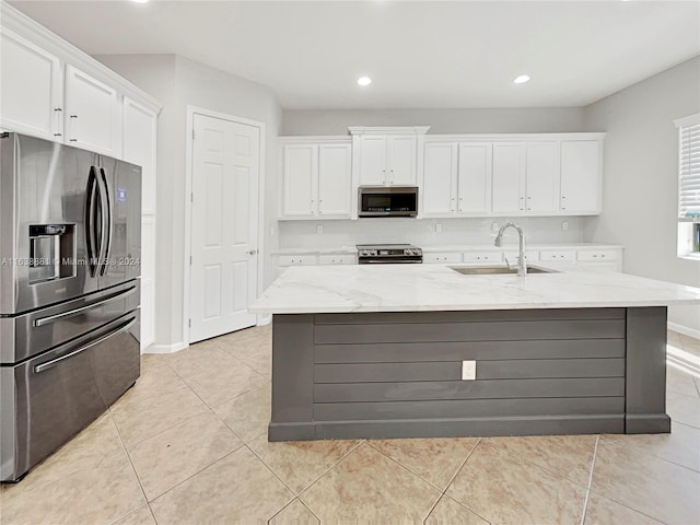 kitchen with light stone countertops, sink, stainless steel appliances, and white cabinetry