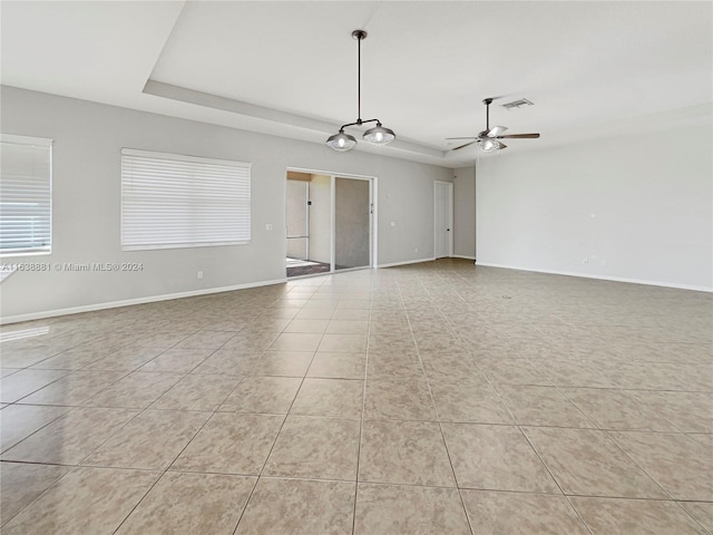 spare room featuring light tile patterned flooring, ceiling fan, and a raised ceiling