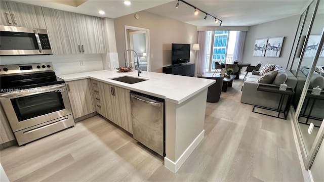 kitchen featuring light brown cabinetry, sink, light hardwood / wood-style flooring, kitchen peninsula, and stainless steel appliances