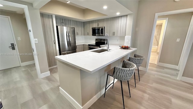 kitchen with light hardwood / wood-style floors, stainless steel appliances, kitchen peninsula, and a kitchen bar