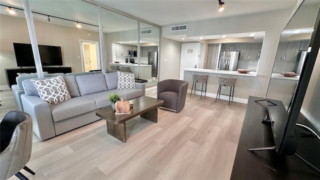 living room with rail lighting and light wood-type flooring