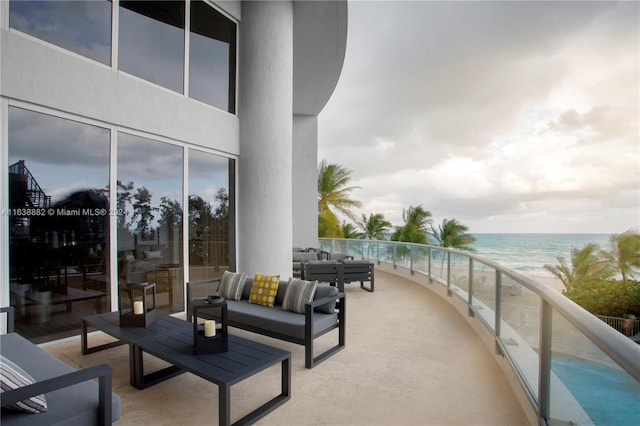 balcony featuring a water view, a beach view, and an outdoor living space