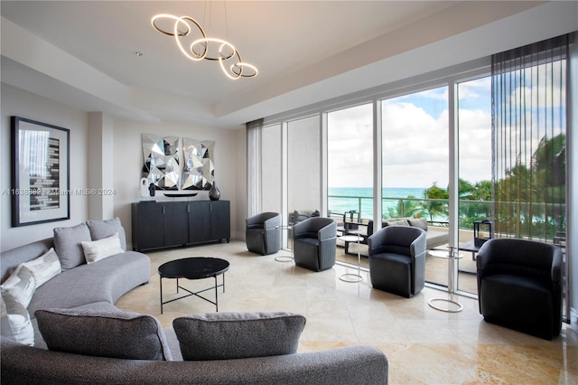 living room featuring an inviting chandelier, a tray ceiling, and a water view