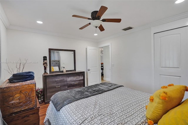 bedroom with ornamental molding, dark wood-type flooring, ceiling fan, and a closet