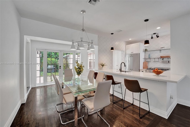 dining space featuring a notable chandelier, sink, dark hardwood / wood-style flooring, and french doors