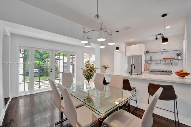 dining space featuring dark hardwood / wood-style floors, sink, and an inviting chandelier