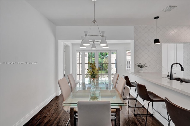 dining room featuring sink, dark wood-type flooring, and an inviting chandelier