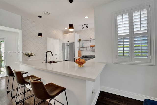 kitchen with high end fridge, a kitchen breakfast bar, sink, backsplash, and kitchen peninsula