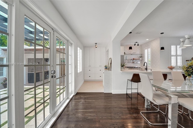 interior space featuring hanging light fixtures, backsplash, hardwood / wood-style flooring, white cabinets, and kitchen peninsula