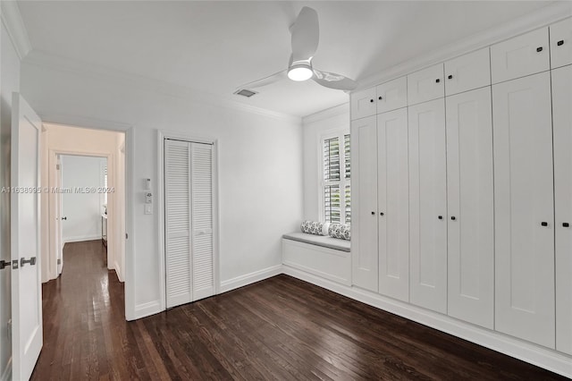 unfurnished bedroom with ceiling fan, multiple closets, ornamental molding, and dark hardwood / wood-style floors