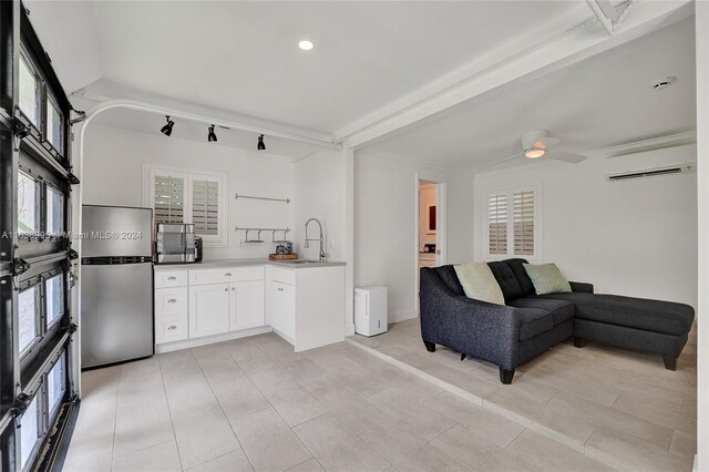 kitchen featuring white cabinets, ceiling fan, light tile patterned flooring, sink, and an AC wall unit