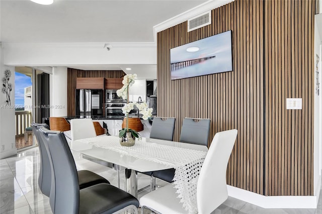 dining room with wood walls and ornamental molding