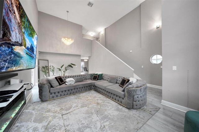 living room featuring wood-type flooring, a notable chandelier, and a towering ceiling