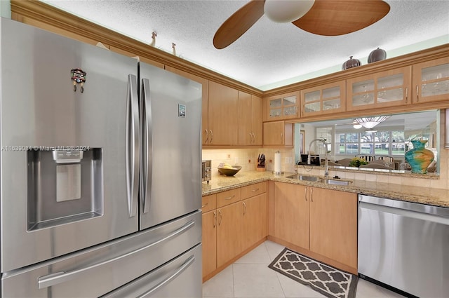 kitchen featuring light tile patterned floors, stainless steel appliances, a sink, a ceiling fan, and tasteful backsplash