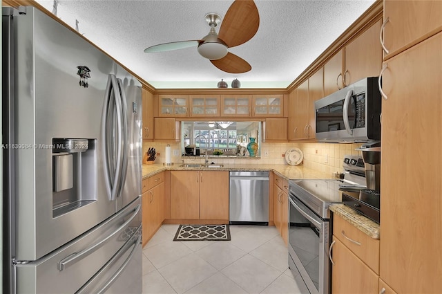 kitchen featuring ceiling fan, stainless steel appliances, light tile patterned floors, tasteful backsplash, and sink