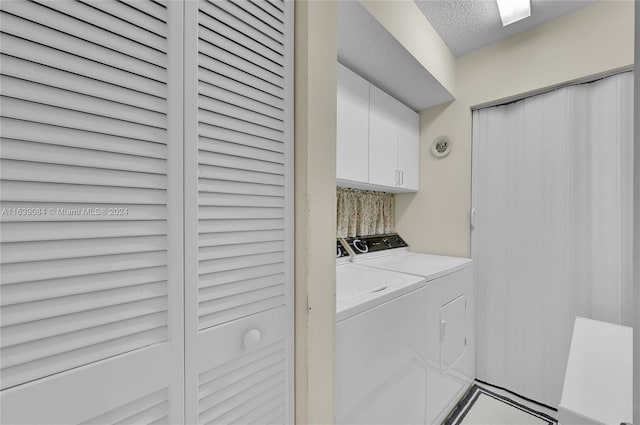 clothes washing area with cabinet space, a textured ceiling, and independent washer and dryer