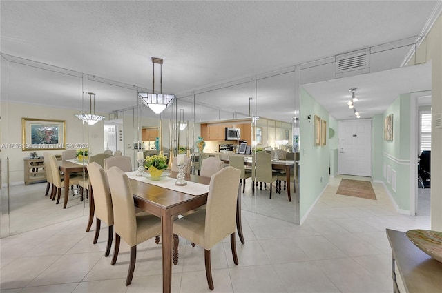 dining space featuring visible vents, a textured ceiling, baseboards, and light tile patterned flooring