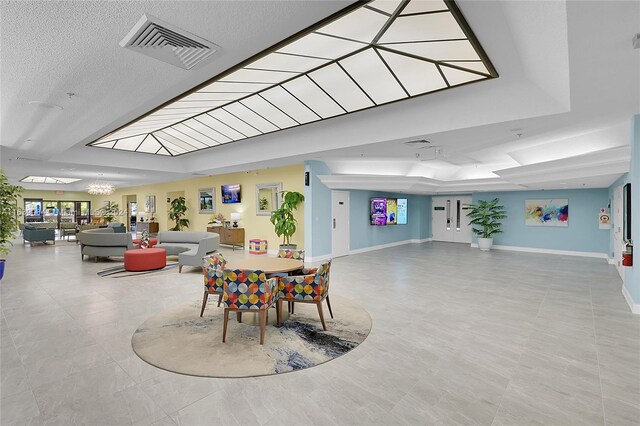 dining space featuring light tile patterned flooring, a textured ceiling, and a tray ceiling