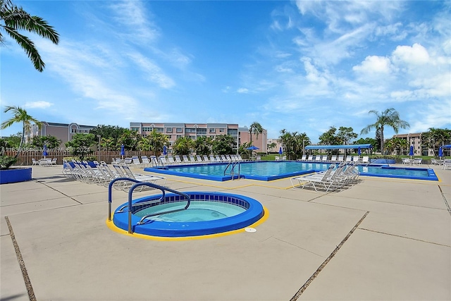 pool featuring a community hot tub, fence, and a patio