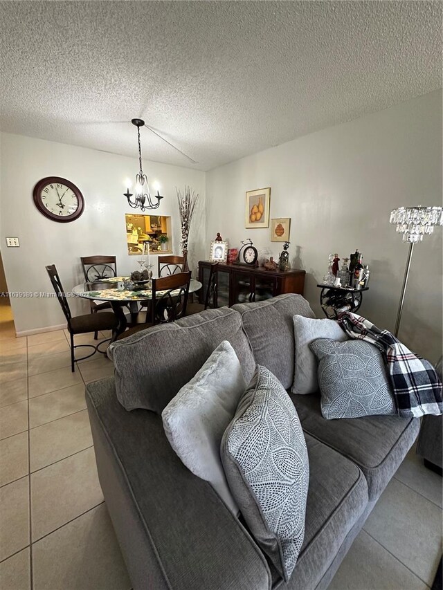 living area with a textured ceiling, an inviting chandelier, and light tile patterned floors