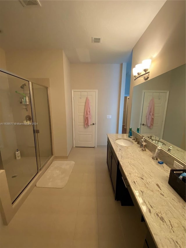 bathroom with a shower with shower door, vanity, and tile patterned floors