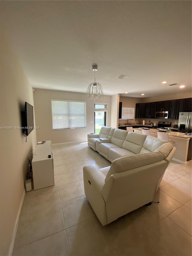 tiled living room with a notable chandelier