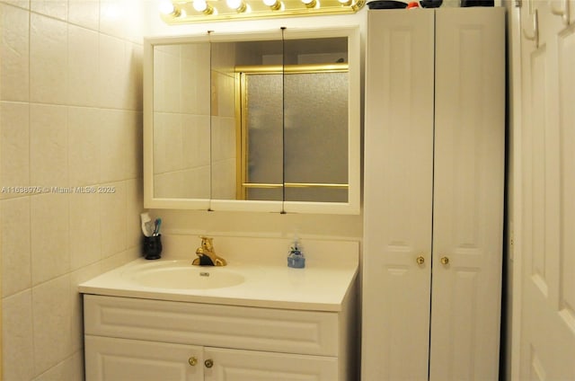 bathroom with tile walls, a shower with shower door, and vanity