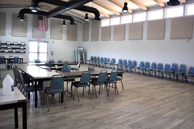 dining area with wood-type flooring, a wealth of natural light, and beamed ceiling