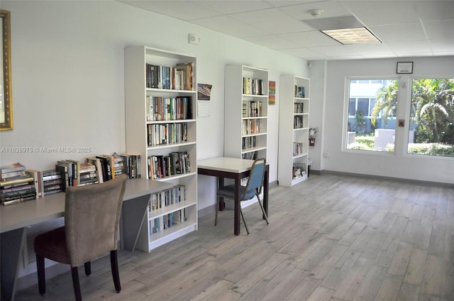 office area with light hardwood / wood-style floors and a paneled ceiling