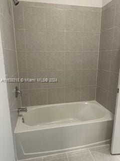 bathroom with tiled shower / bath and tile patterned flooring