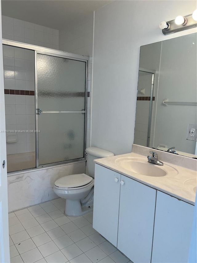 full bathroom with combined bath / shower with glass door, toilet, tile patterned floors, and vanity