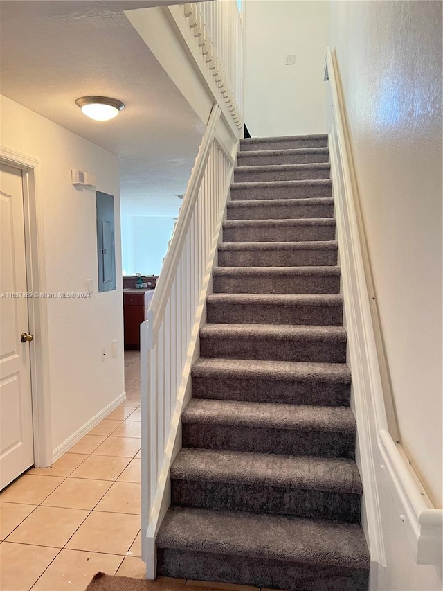 staircase with electric panel and light tile patterned floors