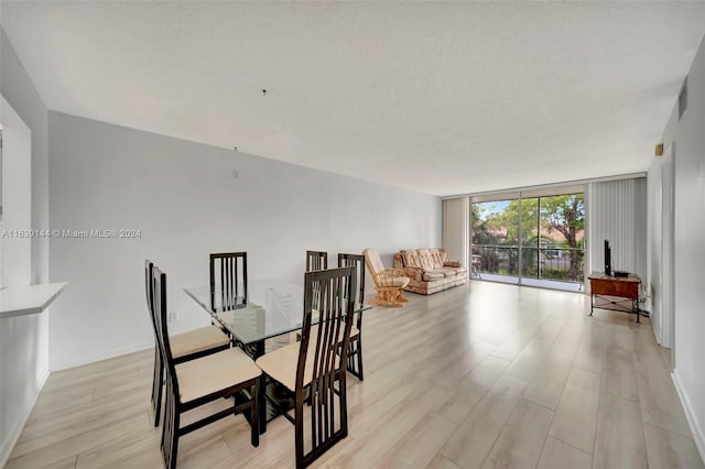 dining room featuring a textured ceiling, floor to ceiling windows, and light hardwood / wood-style floors