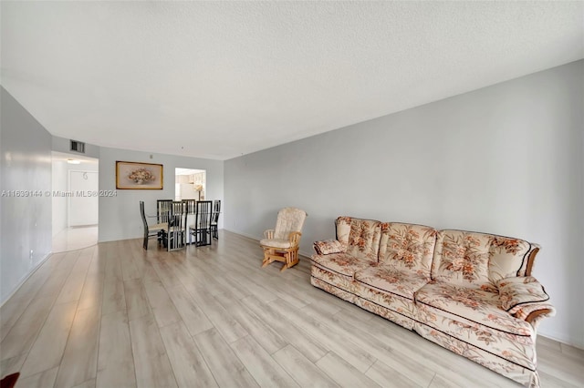 living room featuring light wood-type flooring and a textured ceiling