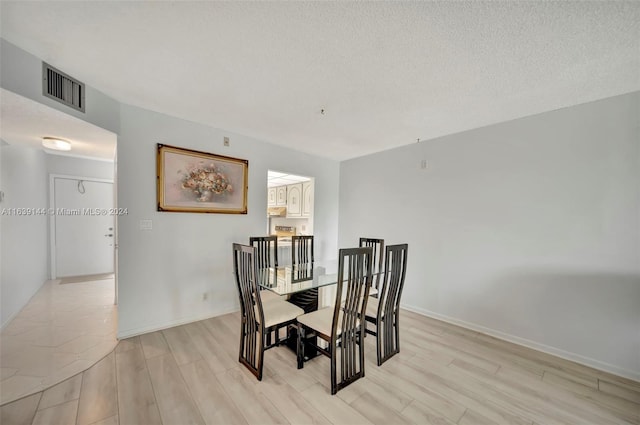 dining space featuring a textured ceiling and light hardwood / wood-style floors