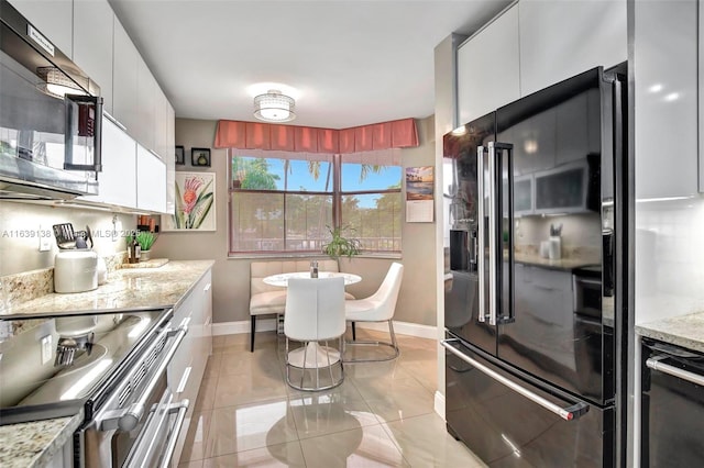 kitchen featuring stainless steel range with electric stovetop, high end black fridge, white cabinets, and light stone countertops