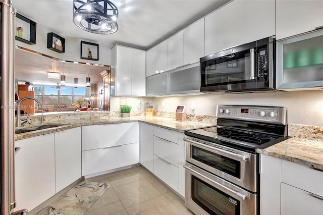 kitchen featuring white cabinets, light stone counters, sink, and range with two ovens