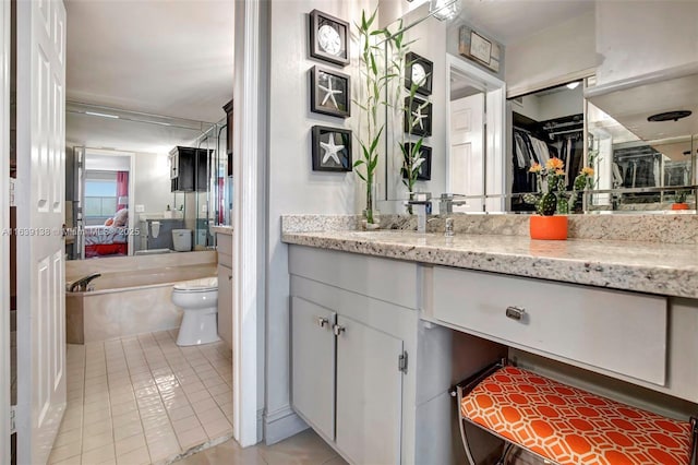 bathroom with tile patterned floors, vanity, toilet, and a tub to relax in