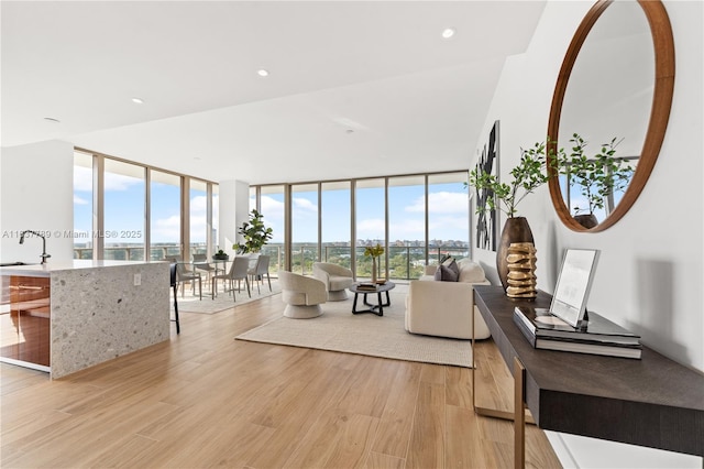 living room with floor to ceiling windows, sink, and light hardwood / wood-style floors