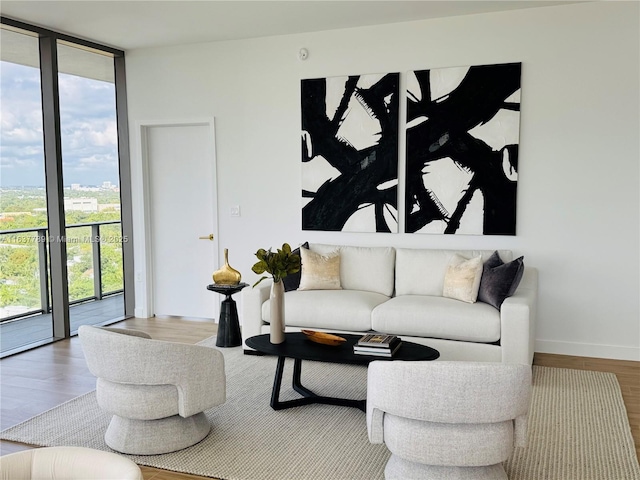 living area with a wall of windows, baseboards, a healthy amount of sunlight, and wood finished floors