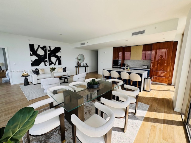 dining room with baseboards, visible vents, and light wood-type flooring