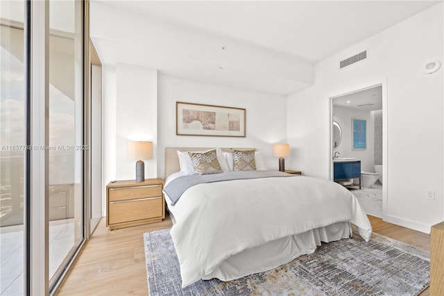 bedroom featuring connected bathroom and light hardwood / wood-style floors