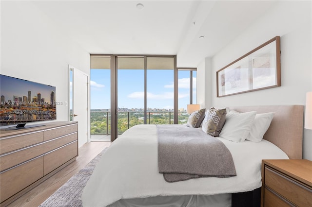 bedroom featuring access to exterior, light hardwood / wood-style flooring, multiple windows, and a wall of windows