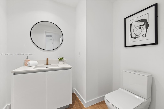bathroom with visible vents, toilet, wood finished floors, baseboards, and vanity