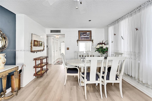 dining space featuring light hardwood / wood-style floors and a textured ceiling